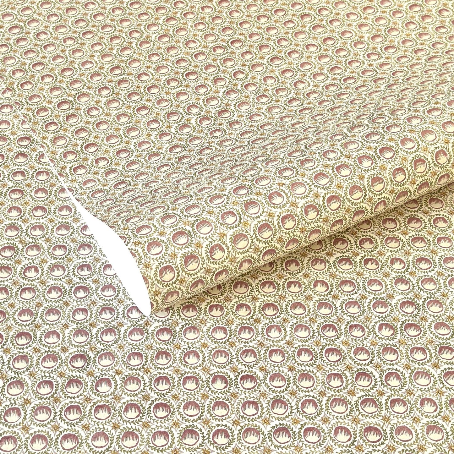 a sheet of wrapping paper with a block printed design of rows of English steam puddings in pink