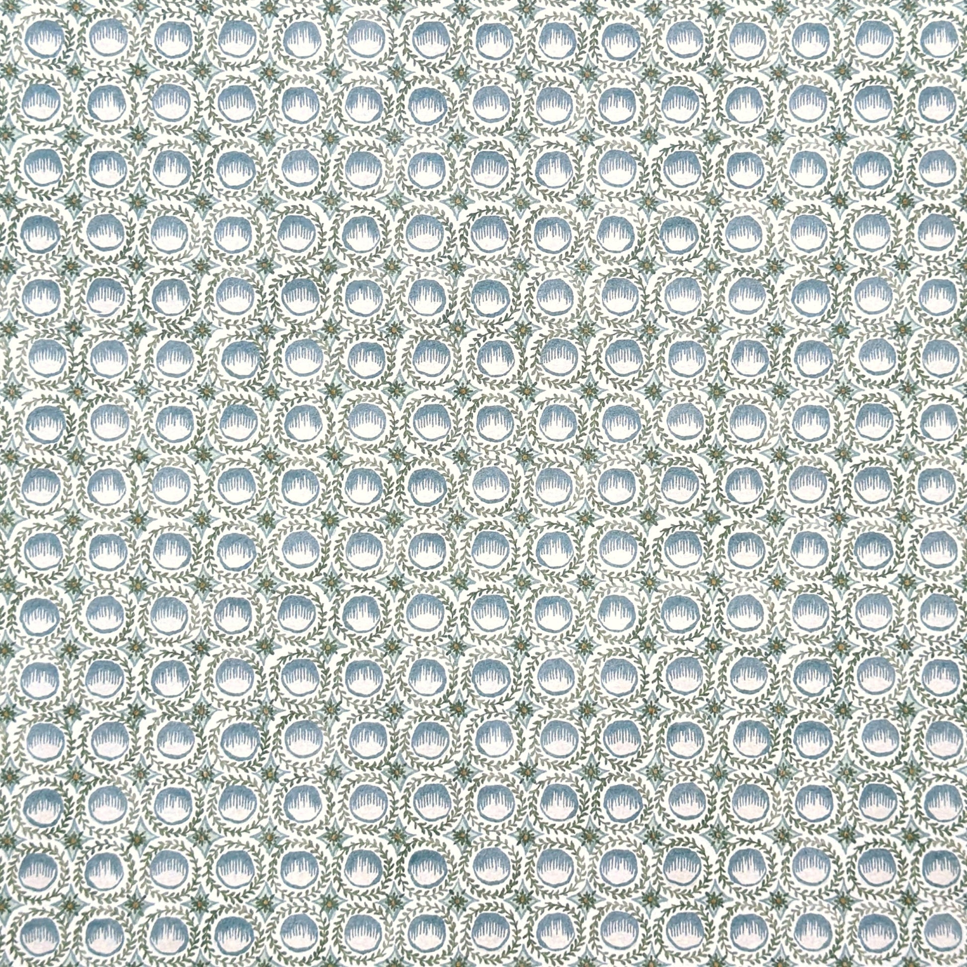 a patterned wrapping paper featuring a repeating botanical design with blue block printed steam puddings, green leafy wreaths, and small yellow accents on a white background.
