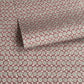 a sheet of wrapping paper by The Kensington Paperie with a small block printed geometric print in white and soft green on a cranberry ground