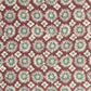 a sheet of wrapping paper by The Kensington Paperie with a small block printed geometric print in white and soft green on a cranberry ground. Close up