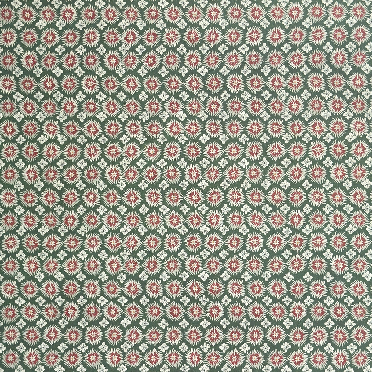 A sheet patterned wrapping paper with a repeating floral medallion design in muted green, dusty pink, and cream by The Kensington Paperie brand