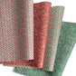 four sheets of wrapping paper from The Kensington Paperie brand.  loosely folded there are two papers with a small stamp deign, one in cranberry and one in green and two marbled designs, one in red and one in green 