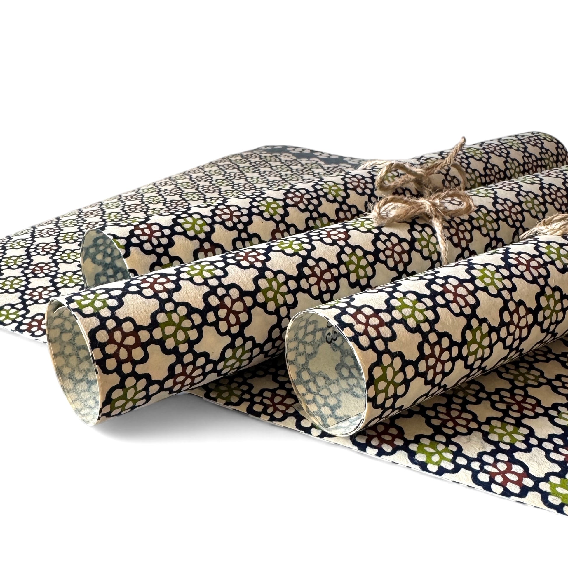 vintage katazome-shi stencil-dyed small papers from Japan. cream paper with a navy, red and green flower pattern. Pictured rolled.