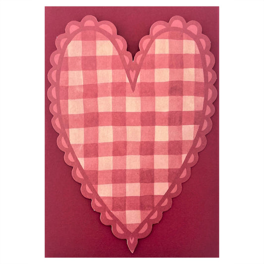 A heart shaped postcard with a red and pink gingham pattern. By Wanderlust, pictured with red envelope