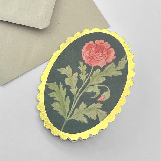 small oval card with an image of a pink rose on a black background. The card has a gold foiled scalloped edge. By Wanderlust. With envelope