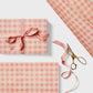 Checkered pattern wrapping paper with pink and beige squares.  Pictured wrapped