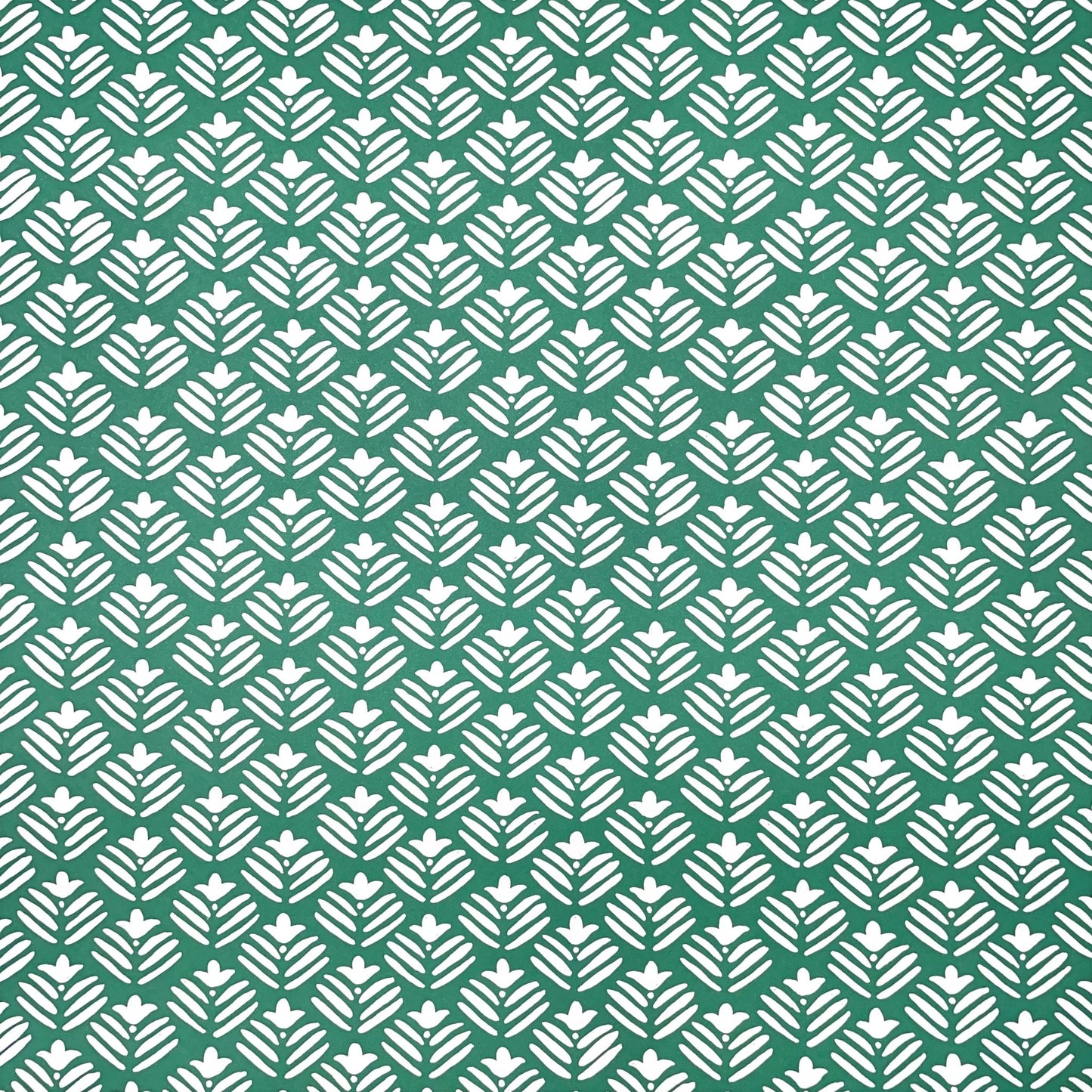 wrapping paper with emerald green backdrop and a white flower repeat pattern by Heather Evelyn