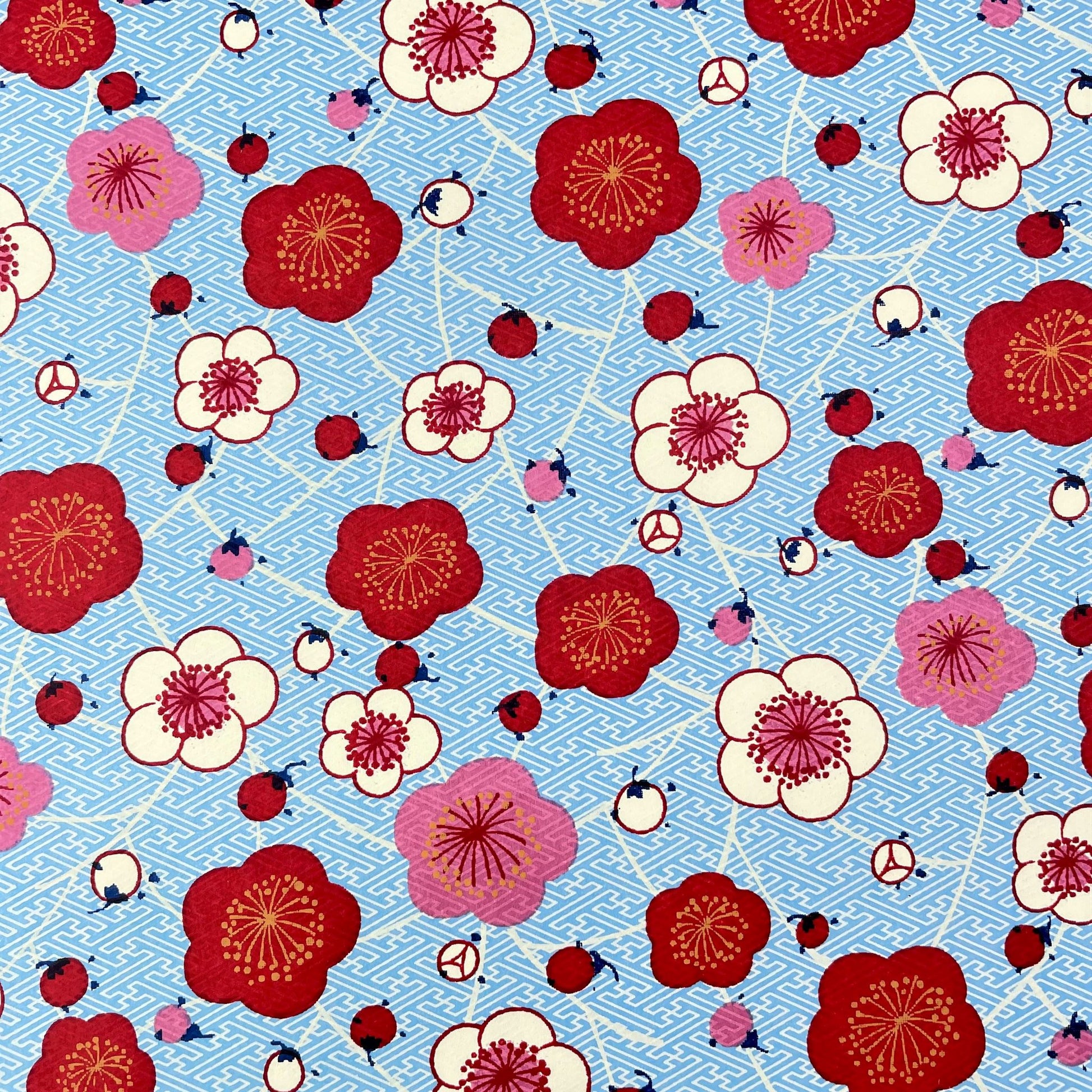 japanese silk-screen handmade paper showing red and pink plum flowers on a blue geometric backdrop