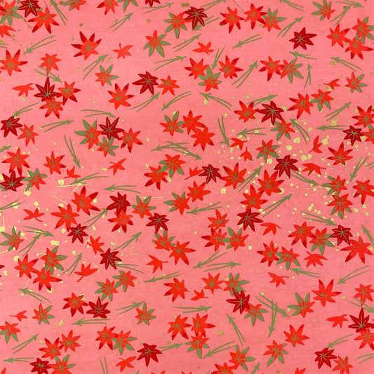 japanese silk-screen handmade paper showing pattern of red falling leaves on coral backdrop and gold highlights
