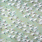 japanese silk-screen handmade paper showing white cranes in flight on a light teal and gold backdrop
