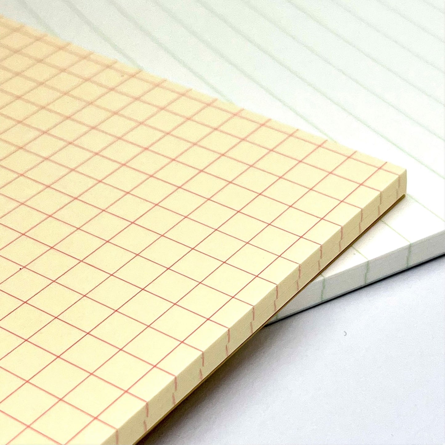 A5 softcover notebook with a soft yellow cover with blue border and branding, close up of the inner cream grid pages