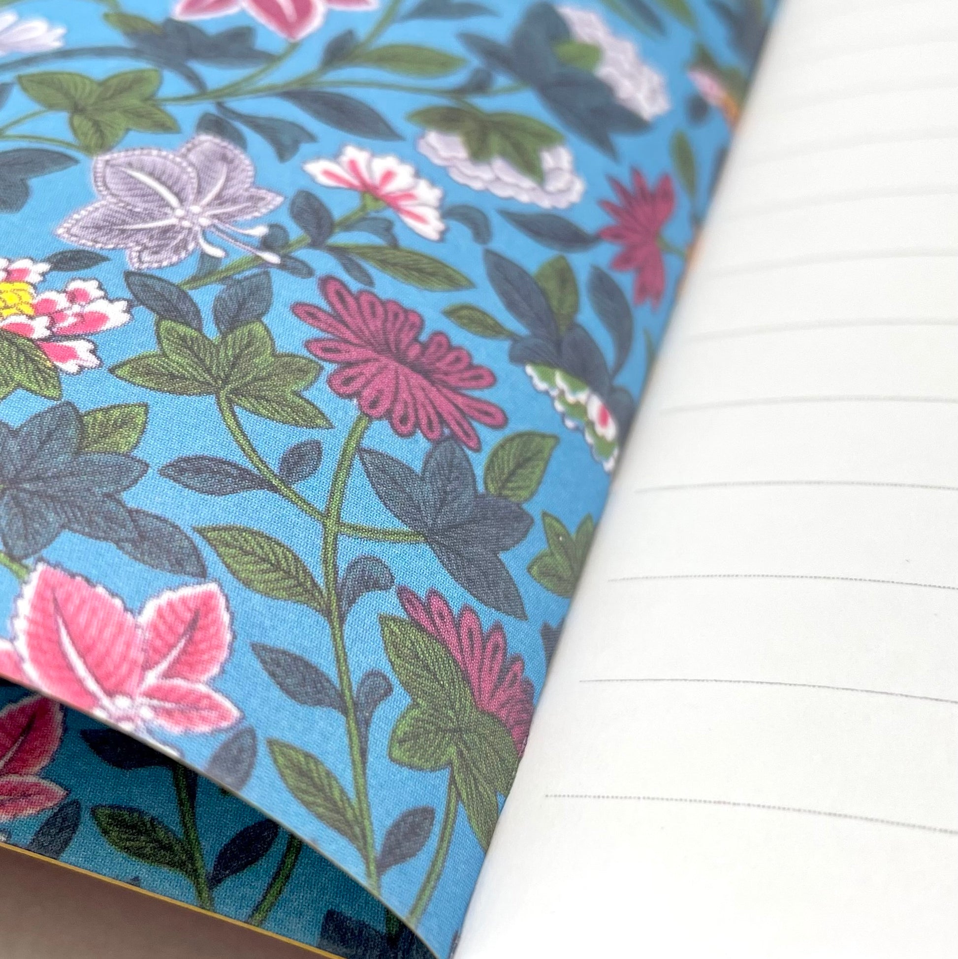 A5 lined notebook with a chinese design of peacock and flowers on a red background, blue floral endpaper close-up