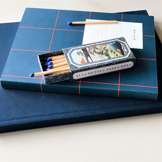Layflat notebook with dark blue softcover with red grid lines, lifestyle shot