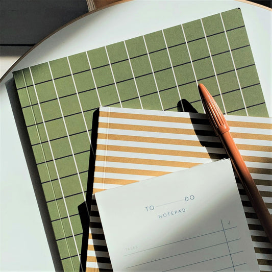 Notebook with a green grid softcover. Lined inner pages, lifestyle image