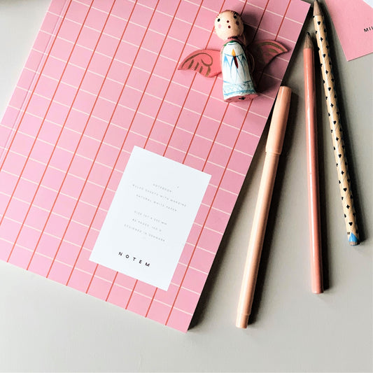 Notebook with a pink grid softcover. Lined inner pages, lifestyle image