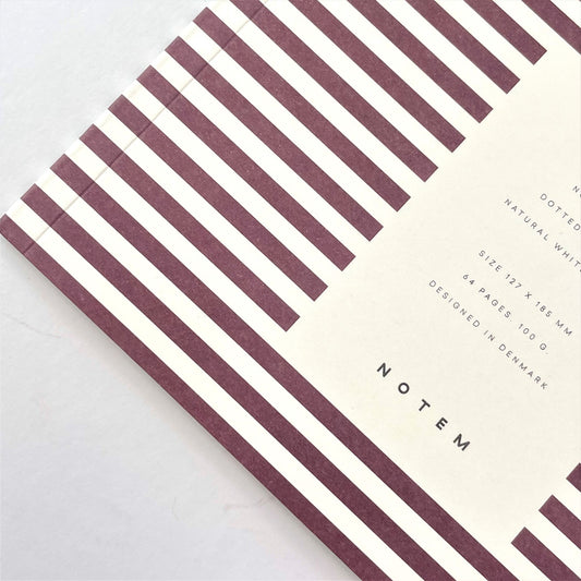 Pocket size notebook with a narrow bordeaux and white stripe softcover. close-up