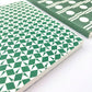 A5 softback notebook with geometric emerald green and white repeat diamond and triangles patterned cover. Dotted inner pages, close-up