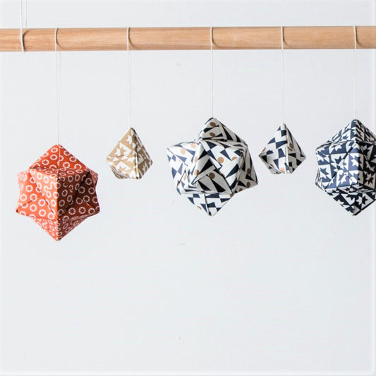 A set of patterned paper origami pyramid and bauble shaped decorations, in colours red, gold, navy and white