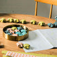 A garland of small paper origami patterned stars "lucky stars" in mustard, teal, aqua and orange, pictured as a garland on a table