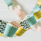 A paperchain of different patterned geometric papers in colours of mustard, orange, aqua and teal