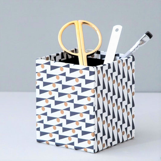 Square pencil pot covered in geometric triangle and dot pattern, navy and gold, patterned paper