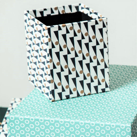 Square pencil pot covered in geometric triangle and dot pattern, navy and gold, patterned paper, lifestyle shot
