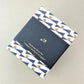 Square pencil pot covered in geometric triangle and dot pattern, navy and gold, patterned paper, pictured with branded belly band