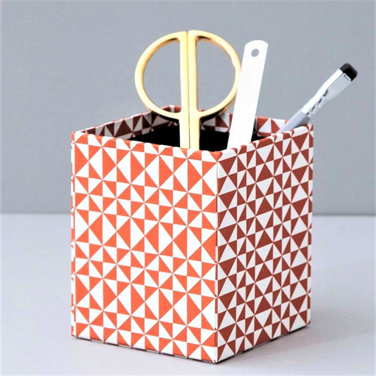 Square pencil pot covered in geometric triangular brick red and white patterned paper