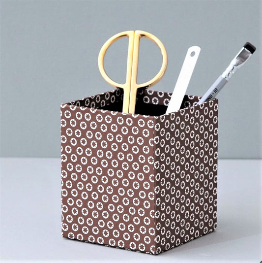 Square pencil pot covered in brown patterned paper with a repeat pattern of tiny white stars