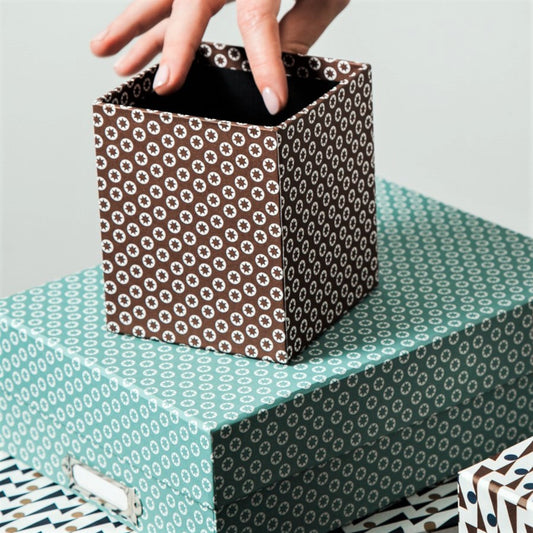Square pencil pot covered in brown patterned paper with a repeat pattern of tiny white stars, lifestyle shot