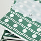 A5 softback 12 week daily planner with geometric green and white circle repeat patterned cover., close-up of a pile of the notebooks